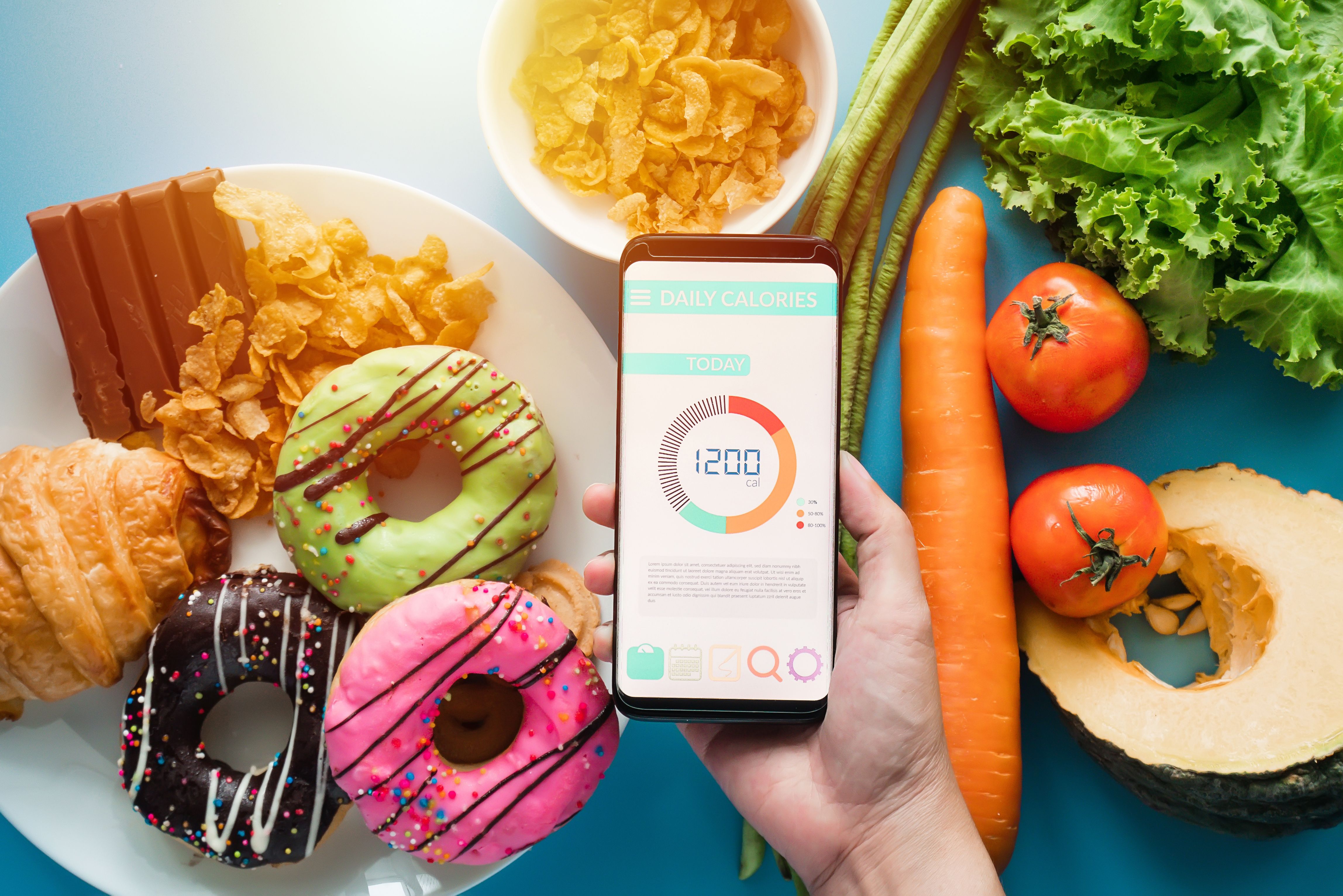 Person tracking calories in app over table of food | Image credit: asiandelight – stock.adobe.com