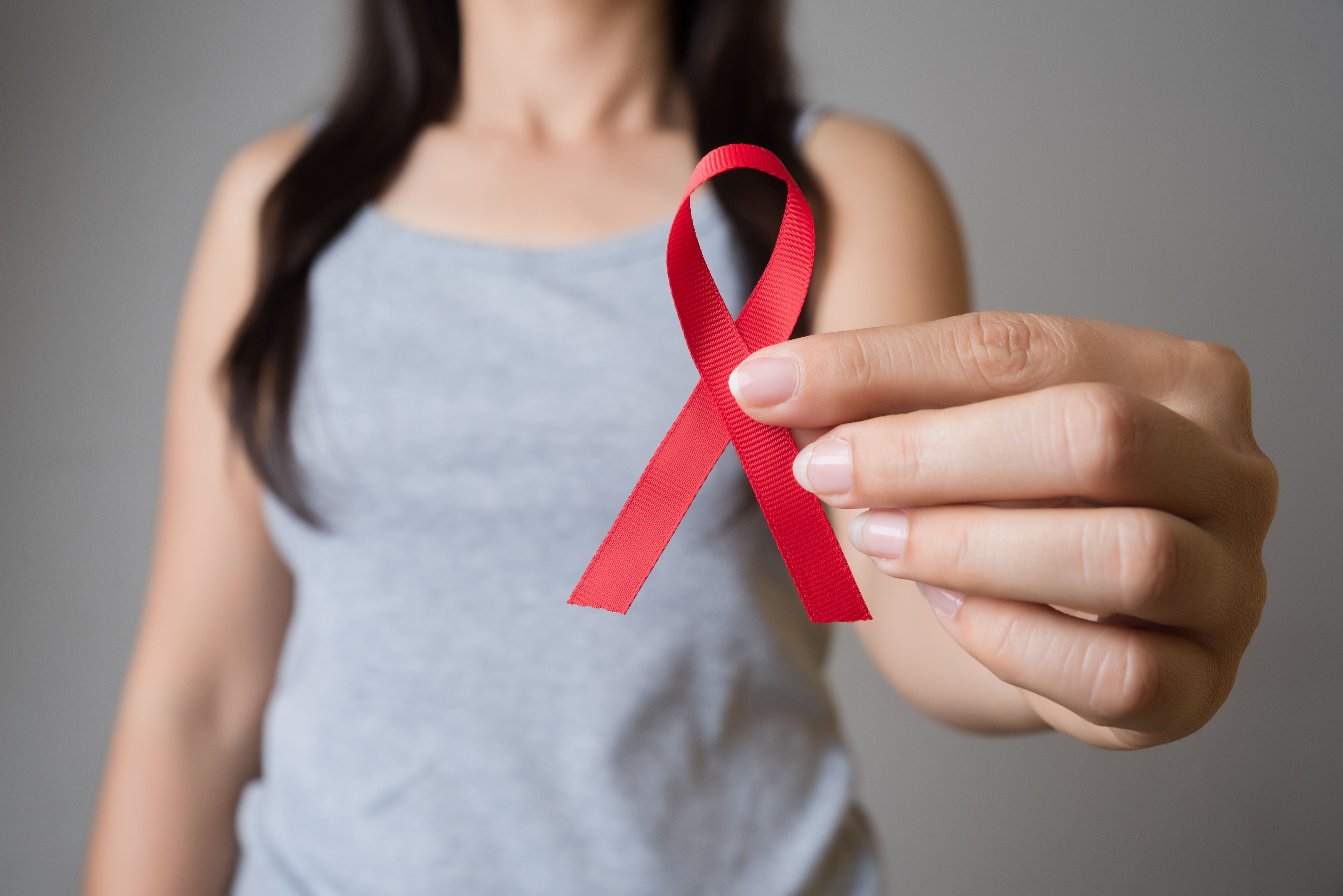 Woman holding AIDS awareness ribbon | Image credit: Siam - stock.adobe.com