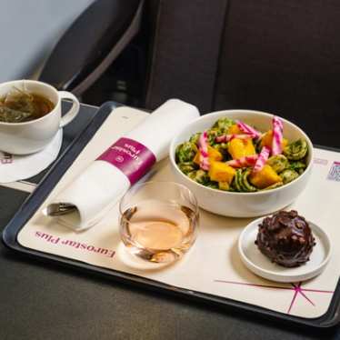 Un repas servi en Eurostar Plus, comprenant un bol de nourriture avec des légumes frais et des ingrédients, un verre de boisson à côté et un dessert au chocolat en accompagnement.