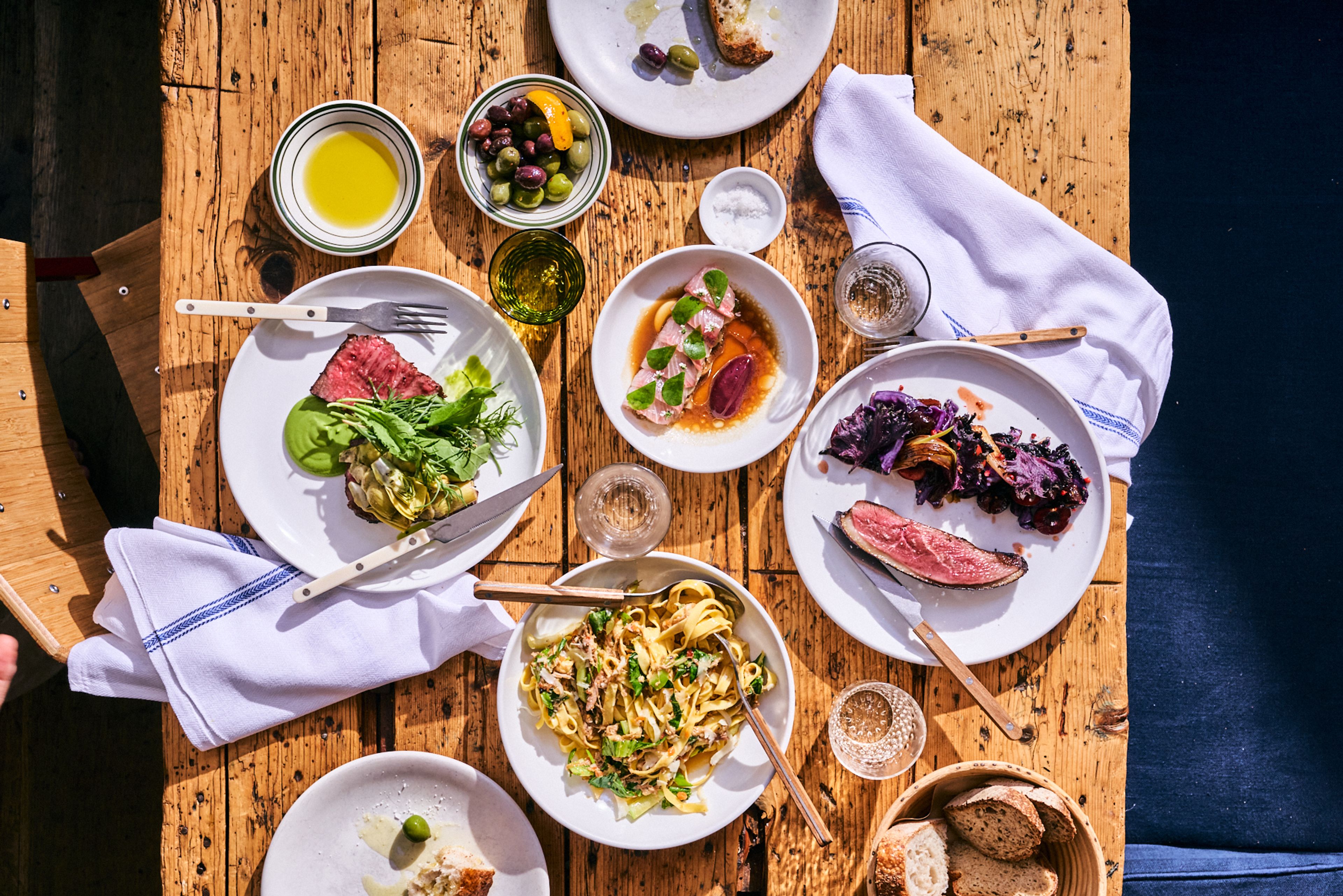 topdown picture of a dinner with meat, pasta, raw fish, and more