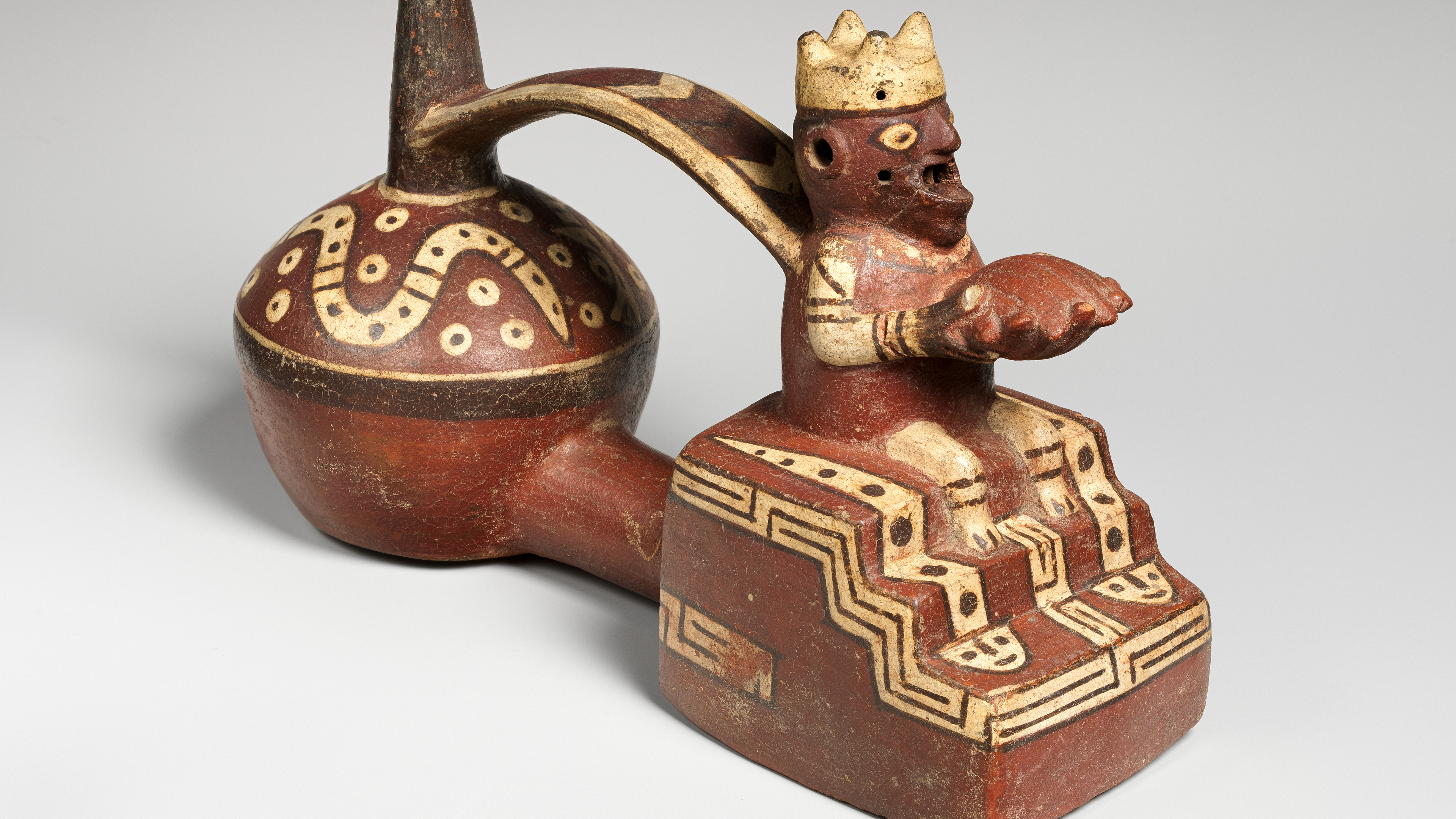 Red and white double-chambered ceramic bottle with a seated human figure holding a Spondylus shell