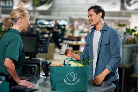 a man is using a cell phone to pay for groceries at a grocery store .